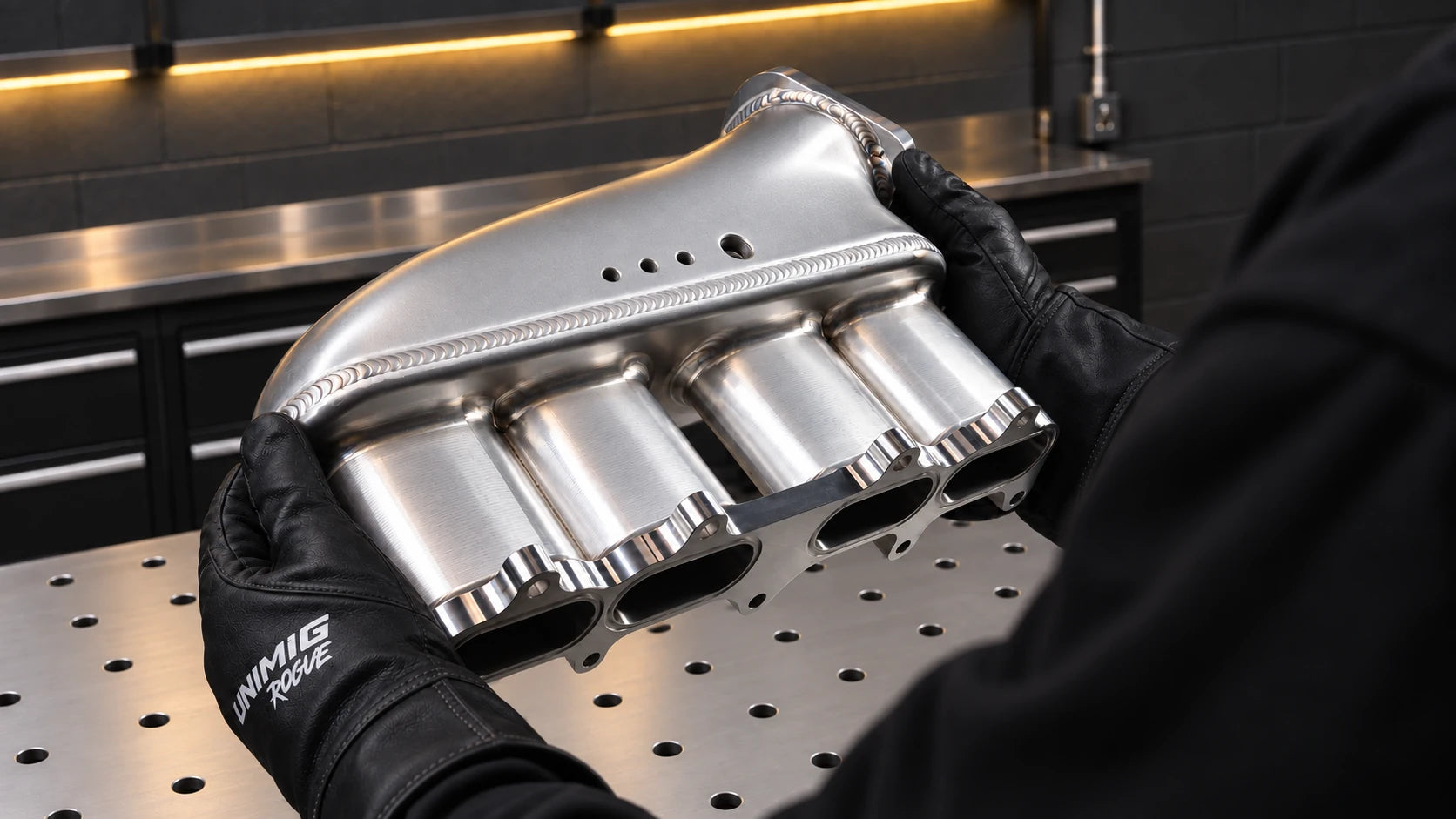 Gloved hands holding a welded aluminium assembly
